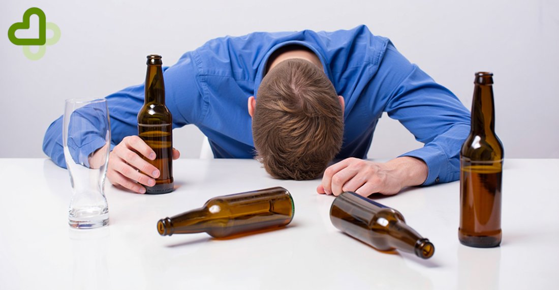 Мужчина лежит за столом с бутылками пива